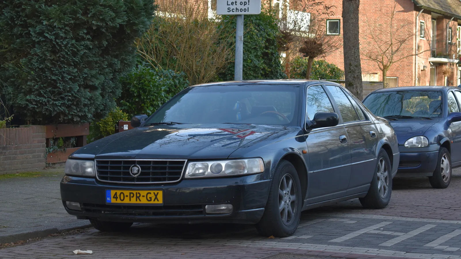Dark blue 1998-2004 Cadillac Seville STS sedan, front three-quarter view, parked on a street