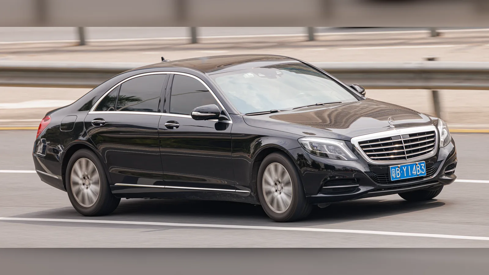 Black Mercedes-Benz S-Class W222 sedan, front three-quarter view, driving on a road