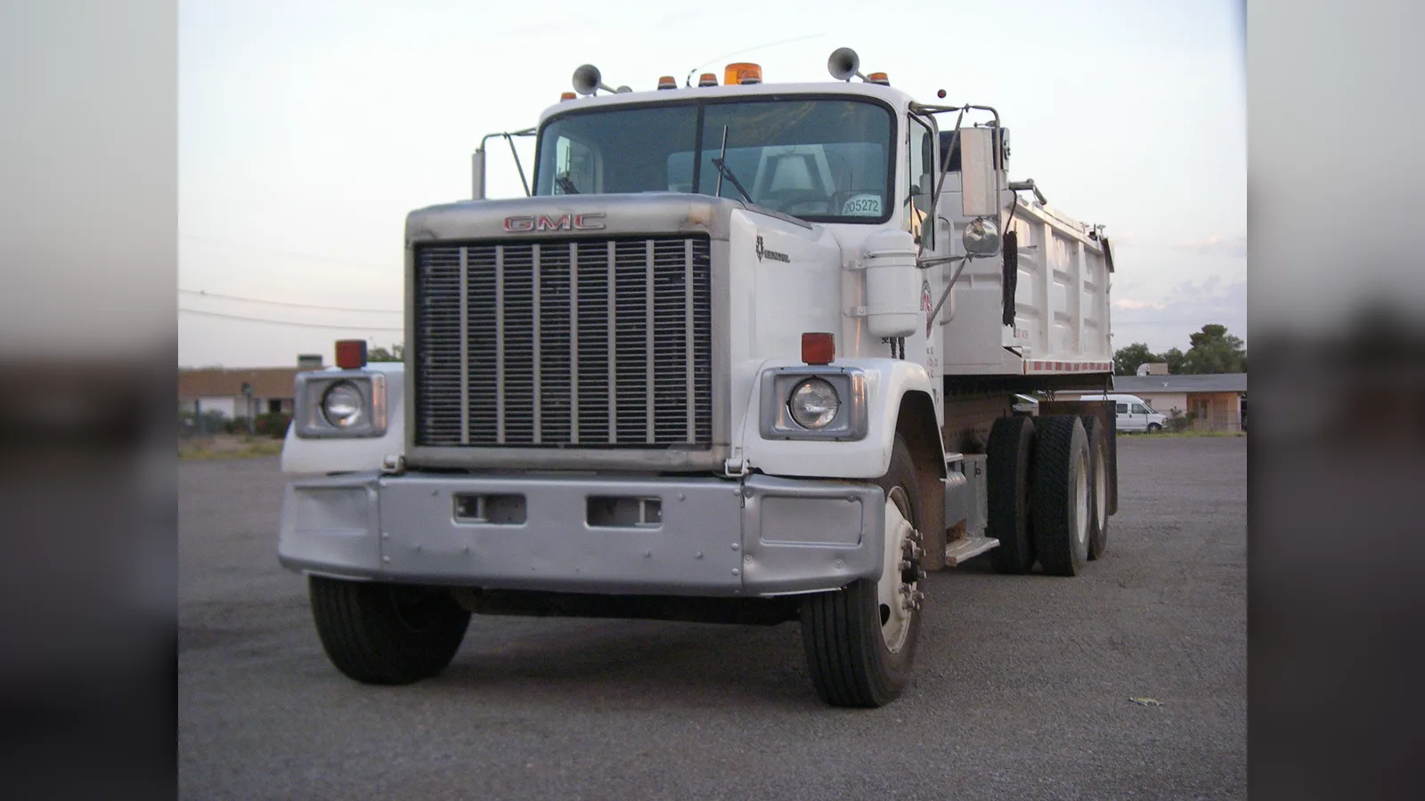 White GMC General dump truck, front three-quarter view, in a parking lot